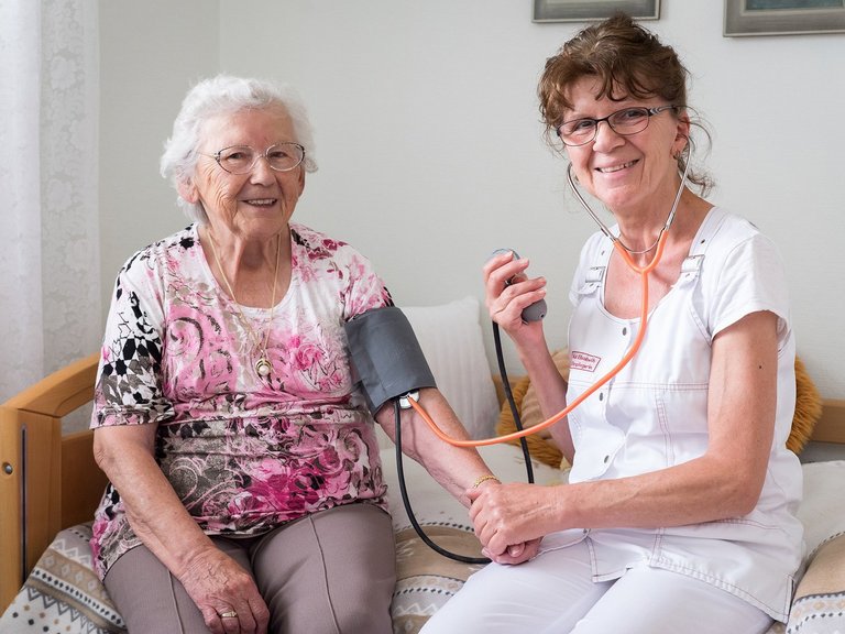 Eine Pflegerin beim Blutdruck-Messen